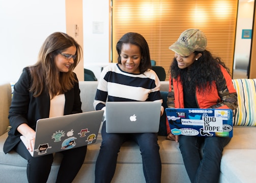 three women sitting on sofa with MacBook