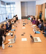 people sitting beside rectangular brown table with laptops